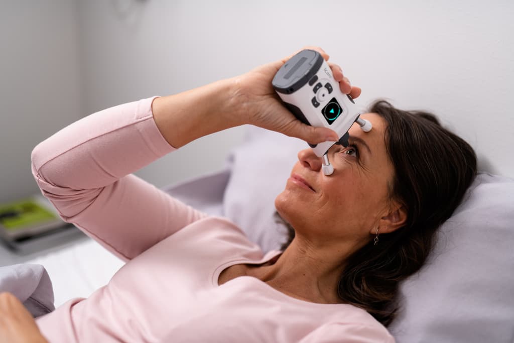 Patient measuring eye pressure while lying down with the iCare HOME2